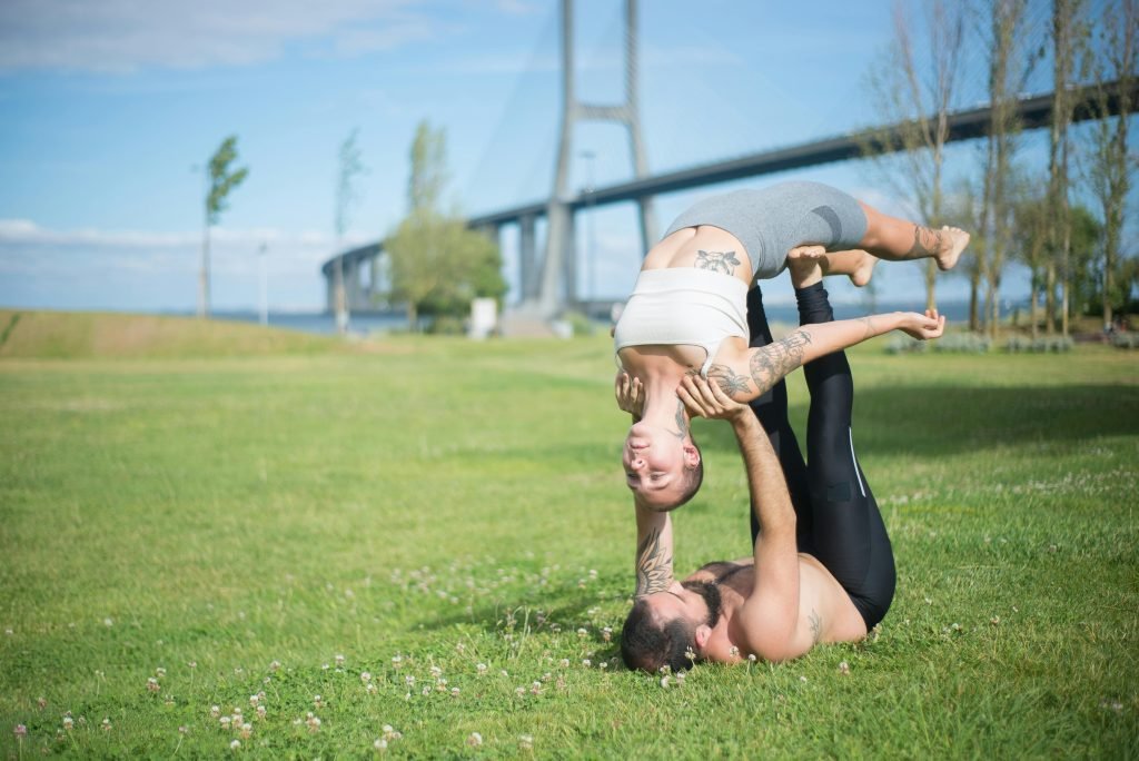 Akrobatisches Paar beim Yoga im Park – Symbolbild für alternative Gesundheitsansätze - Lügen über Gesundheit