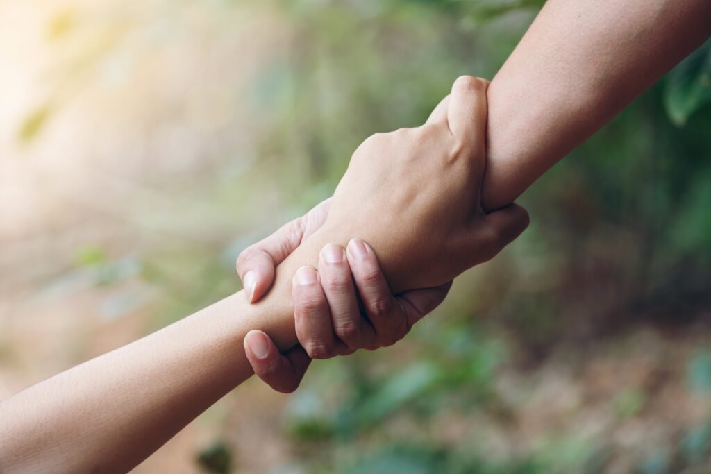 Zwei Menschen halten sich an den Händen – anderen helfen