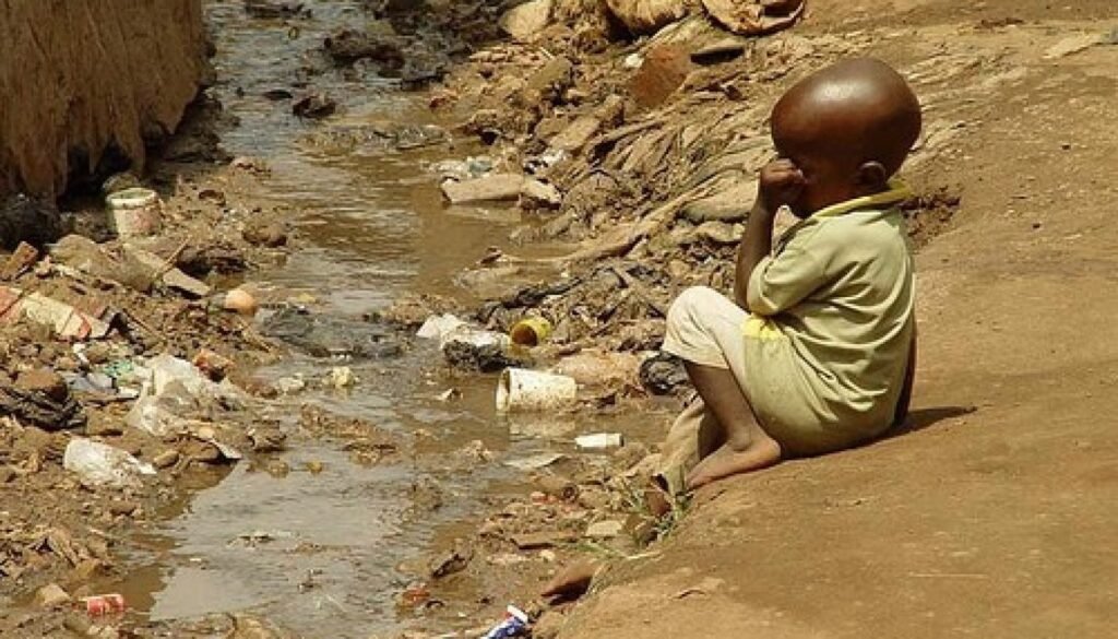 Kleines Kind sitzt am verdreckten Abwassergraben – Symbol für die Nestlé Wasserprivatisierung