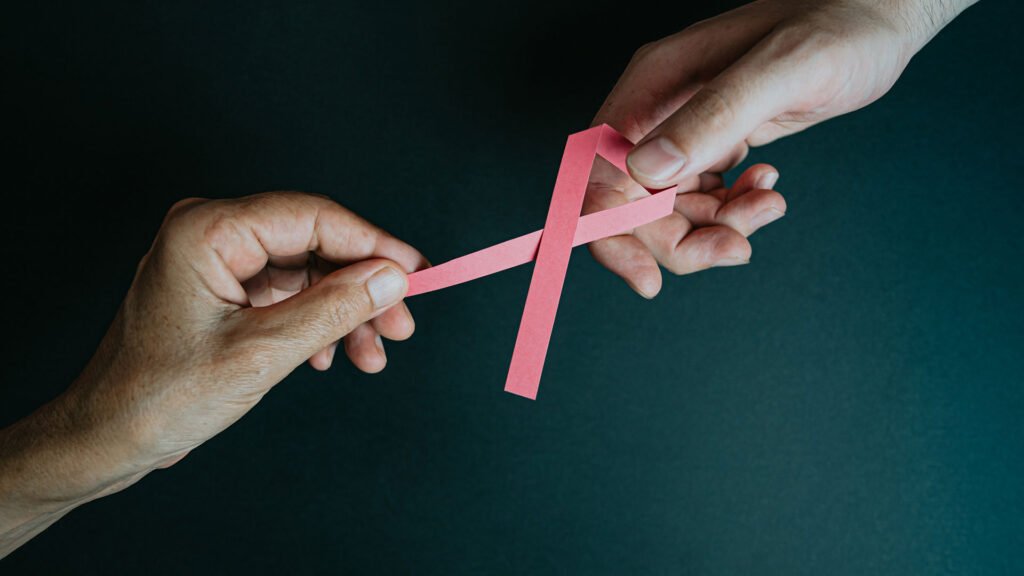 Zwei Hände halten eine rosa Krebsschleife – Symbol für das Bewusstsein über Krebs durch Alltagsgifte