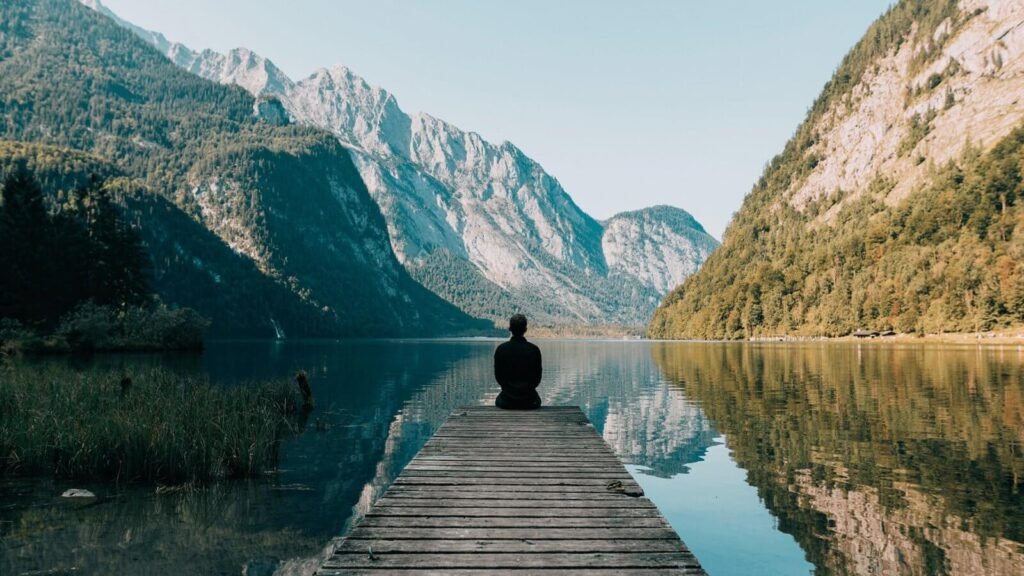 Meditierende Person am Bergsee als Symbol für achtsam leben in der Natur