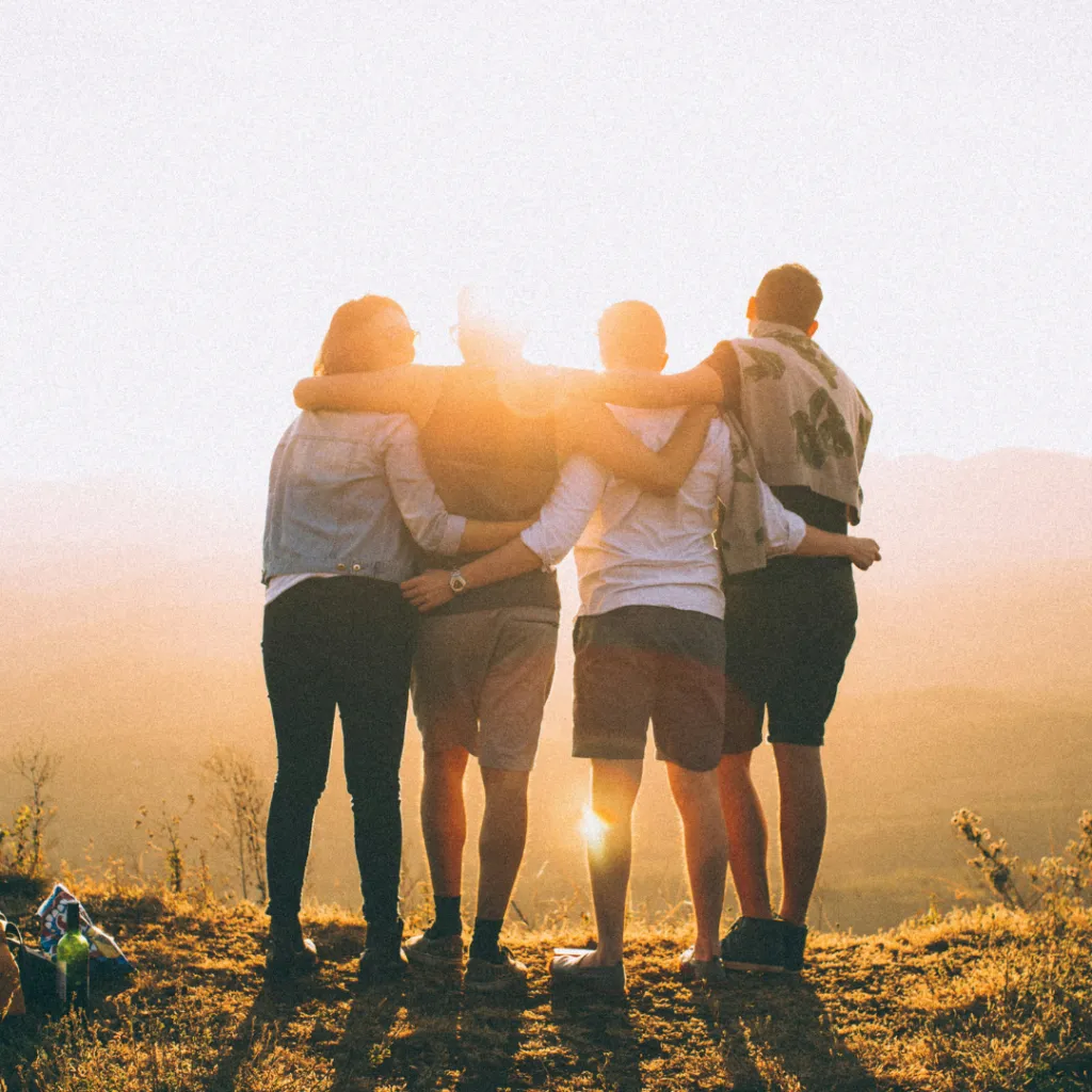 Vier Freunde umarmen sich im Sonnenlicht – Sinnbild für wahre Freundschaft und Zusammenhalt