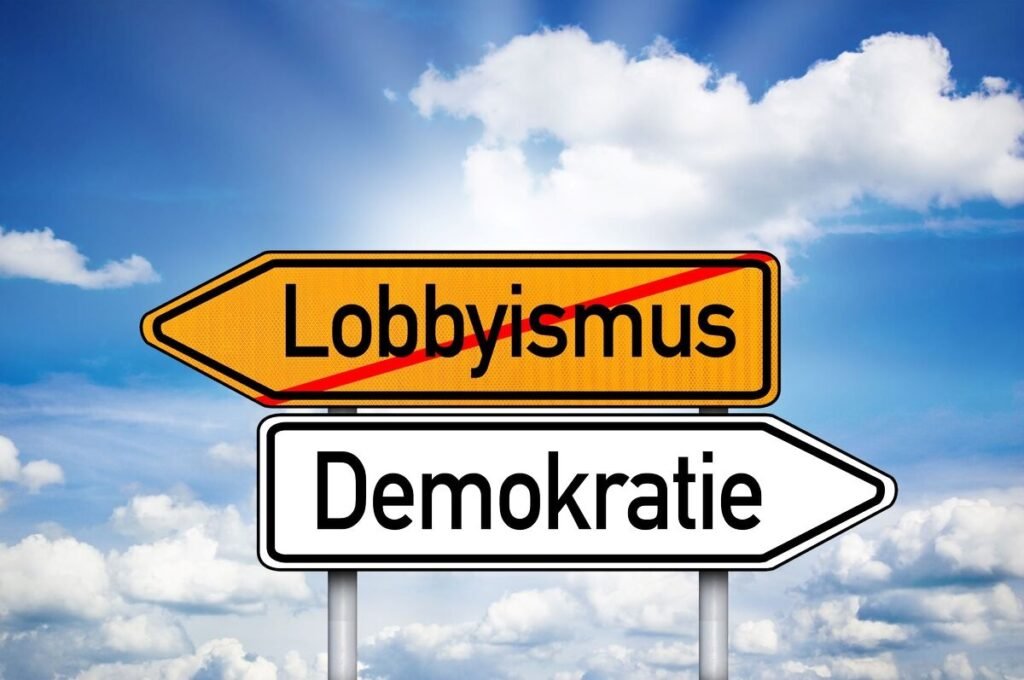 Ein Verkehrsschild zeigt den durchgestrichenen Begriff „Lobbyismus“ und darunter „Demokratie“ – ein klares Statement zu Lobbyismus & Korruption