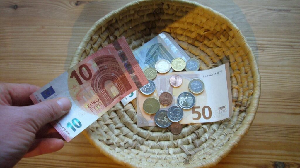 Eine Hand legt Geld in einen Korb – Symbolbild für Mitleid oder Egoismus beim Spenden