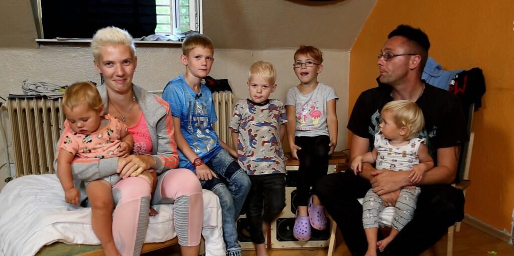 Eine Großfamilie in bescheidenem Wohnraum – Symbol für Kinderkriegen aus Gewohnheit