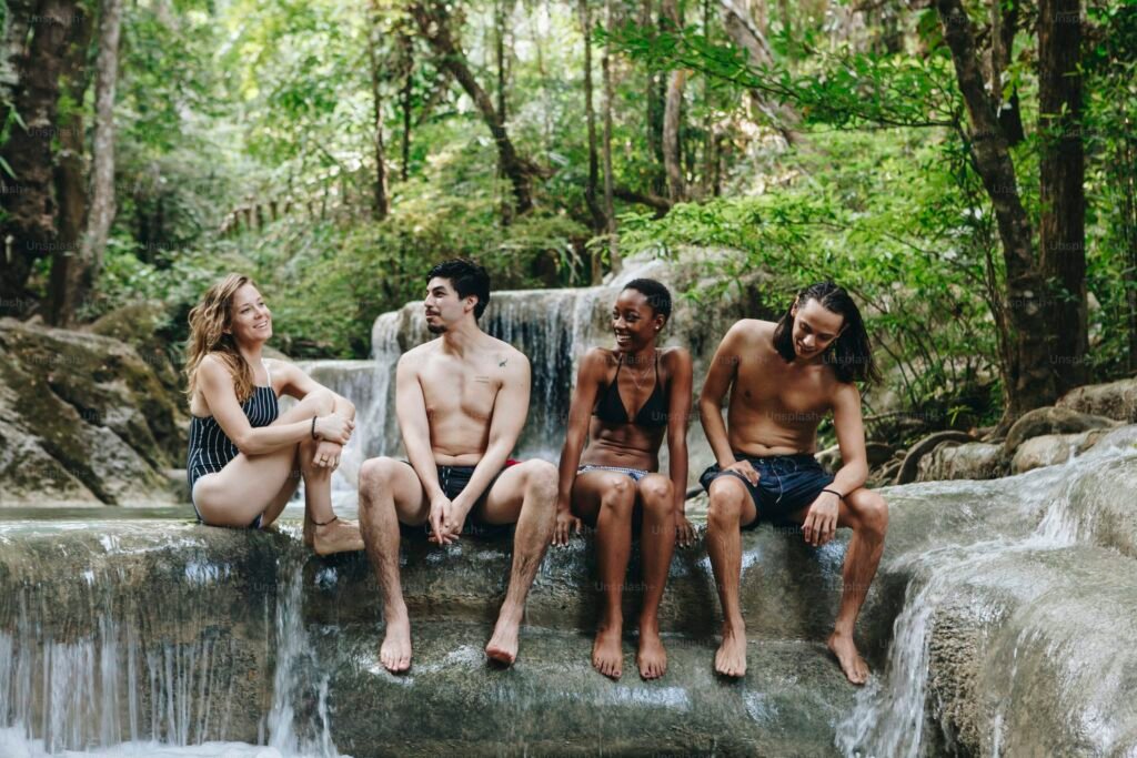 Junge Menschen sitzen entspannt an Wasserfall – neue Lebensstile durch bedingungsloses Grundeinkommen