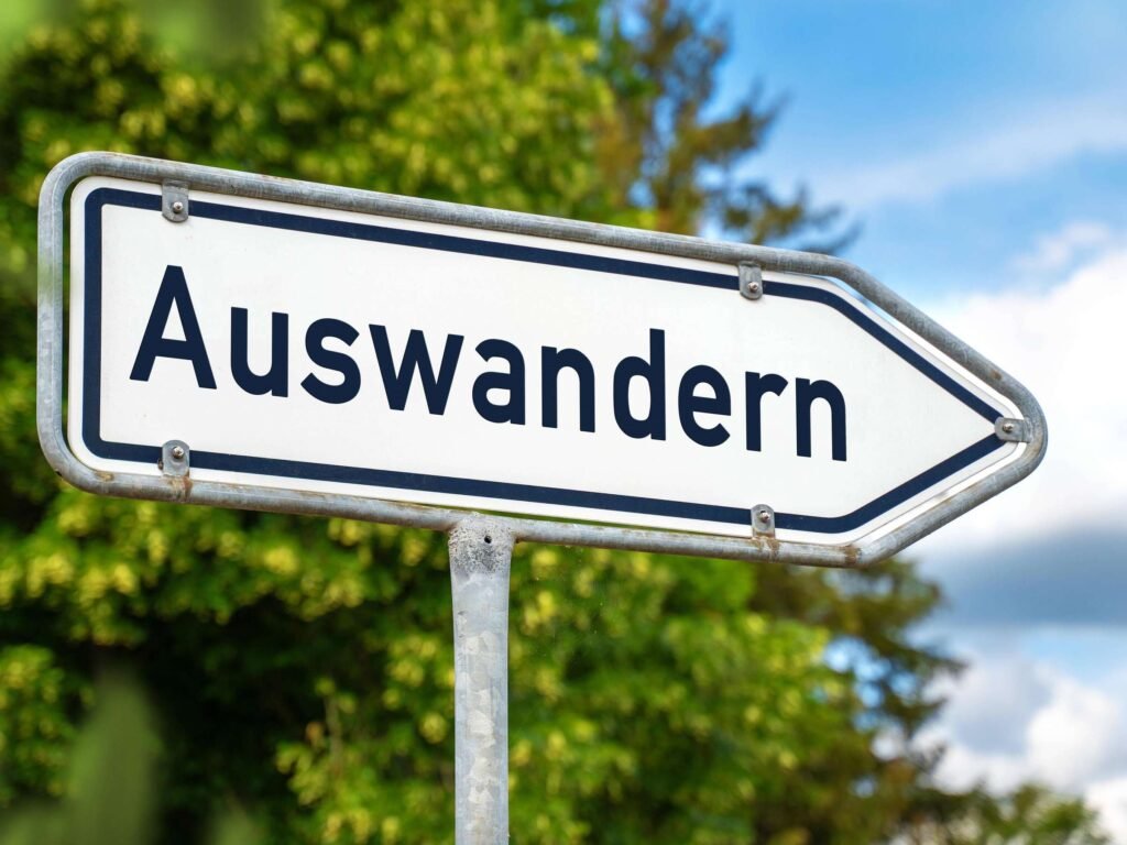 Warum viele Menschen nie auswandern. Wegweiser mit der Aufschrift „Auswandern“ als Symbol für den Wunsch nach Neuanfang